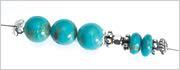 An assortment of metal, magnesite and turquoise gemstone beads strung onto beading wire.